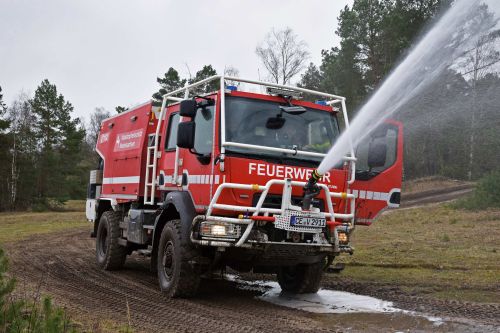 Forest fire-fighting truck in the woods: strong water jet coming from the nozzle at the front of the vehicle