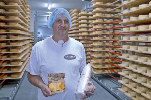 Managing Director Roland Rüegg holding cheese products in his hand