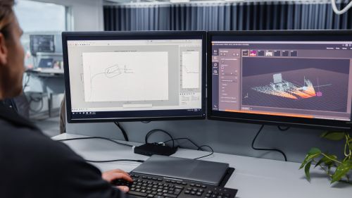 A person is sitting in front of two screens.