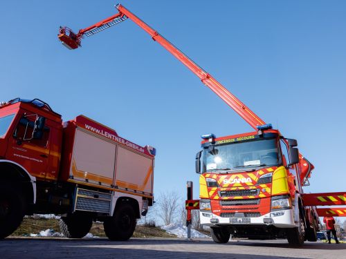 Two fire engines parked side by side outdoors, one with its telescopic boom extended