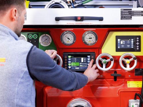 A person operates the pump system on a fire engine