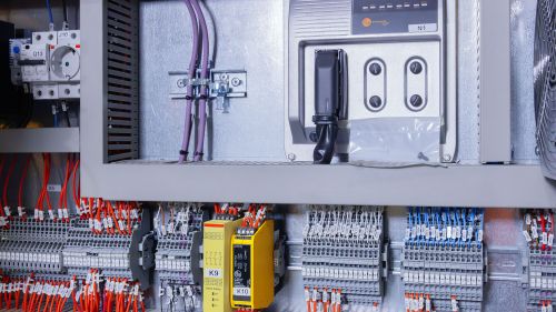 The ifm controller is housed in the control cabinet. Numerous connections and the ifm safety switching devices can be seen.