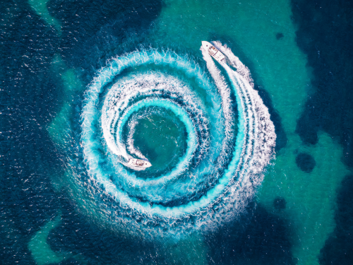 Aerial view of two speedboats travelling at high speed across the sea.