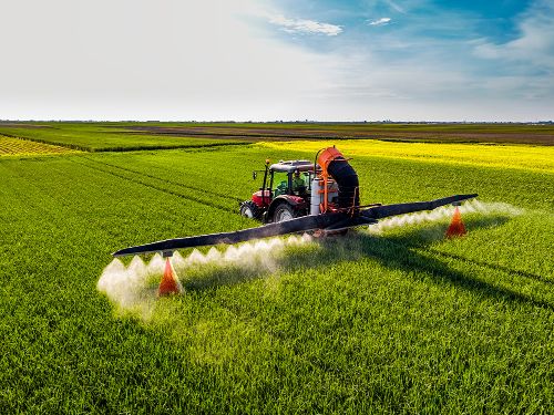 Agricultural sprayer in a field of plants with R1D sensors mounted on either side of the booms