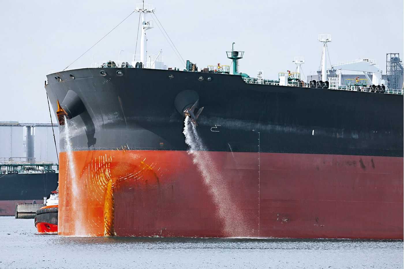 Cargo ship discharging ballast water from hull outlets